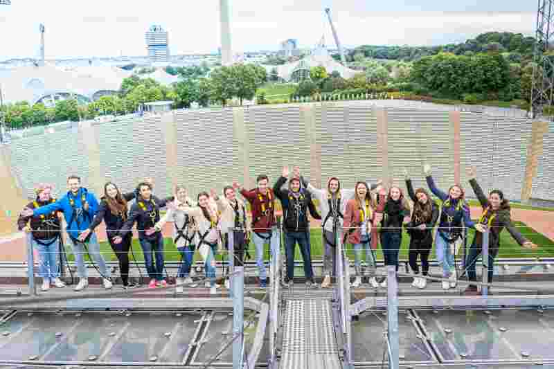 Studenten auf dem Olympia-Dach strecken die Hände in die Höhe