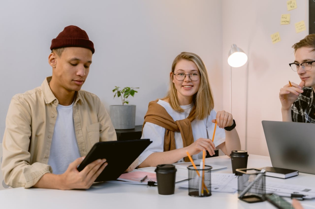 Drei Personen sitzen in einem Büro bei einem Meeting.