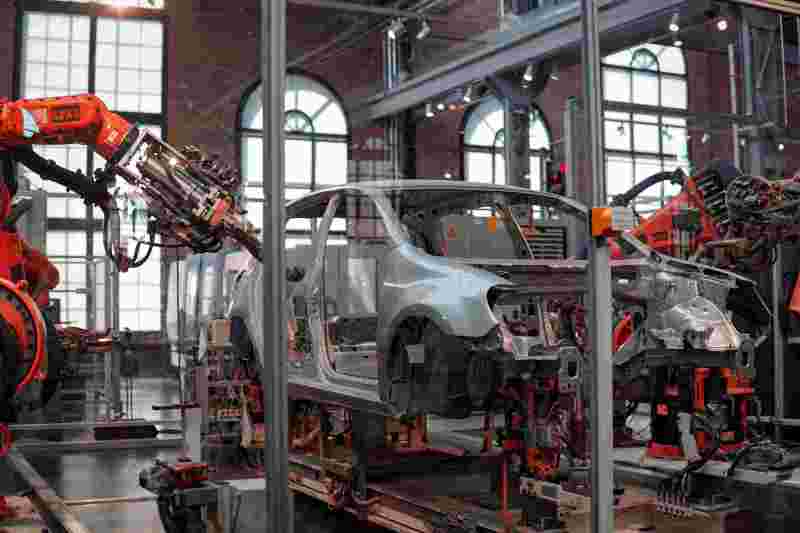 Ein graues Fahrzeug wird in einer Fabrik von Roboter Maschinen repariert.
