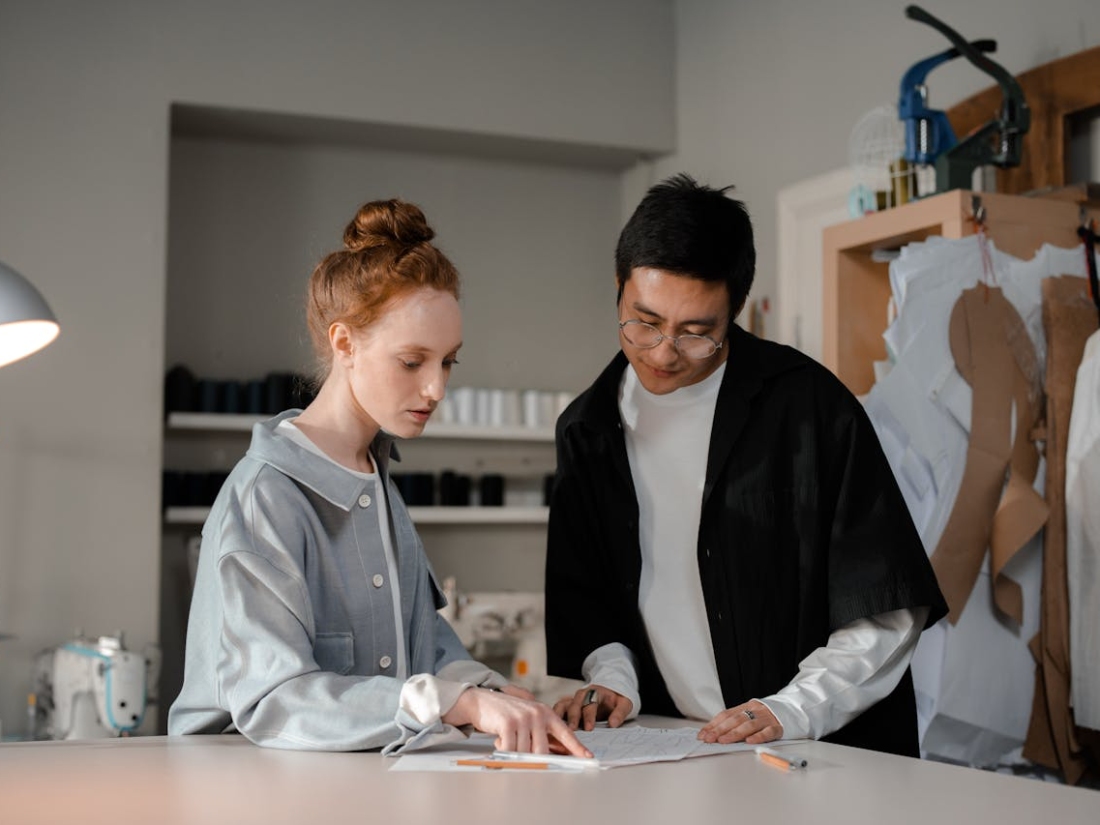 Zwei Personen besprechen Schnitt zeichnungen und Entwürfe in einer Modewerkstatt