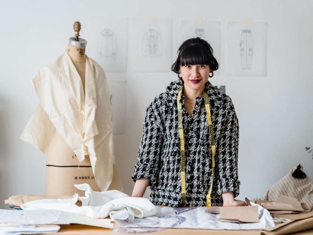 Eine Person arbeitet an Schnitt mustern auf einem Tisch neben einer Schneiderpuppe im Atelier.