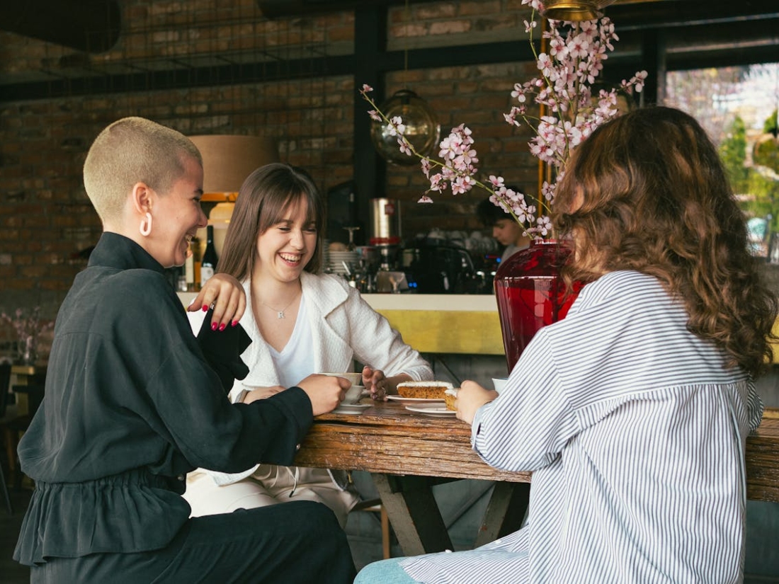Drei Personen sitzen in einem Cafe und lachen und unterhalten sich.