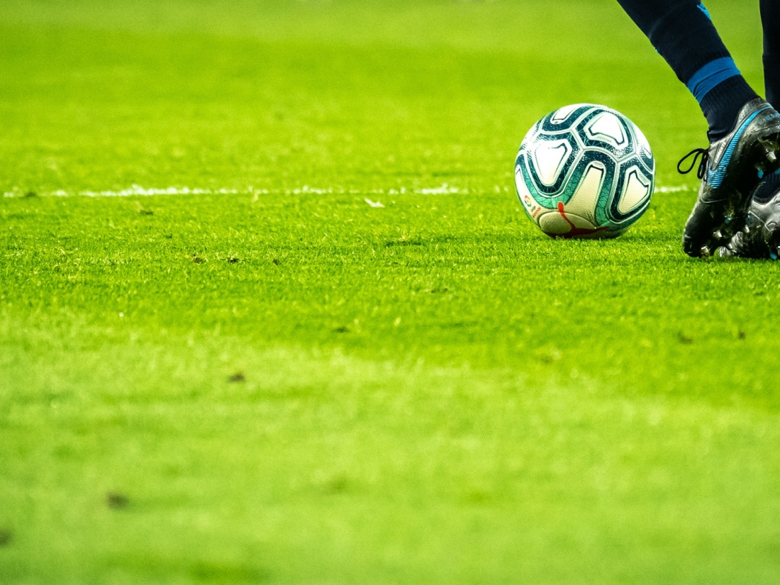 Person spielt Fußball auf dem Feld – Master Sportmanagement