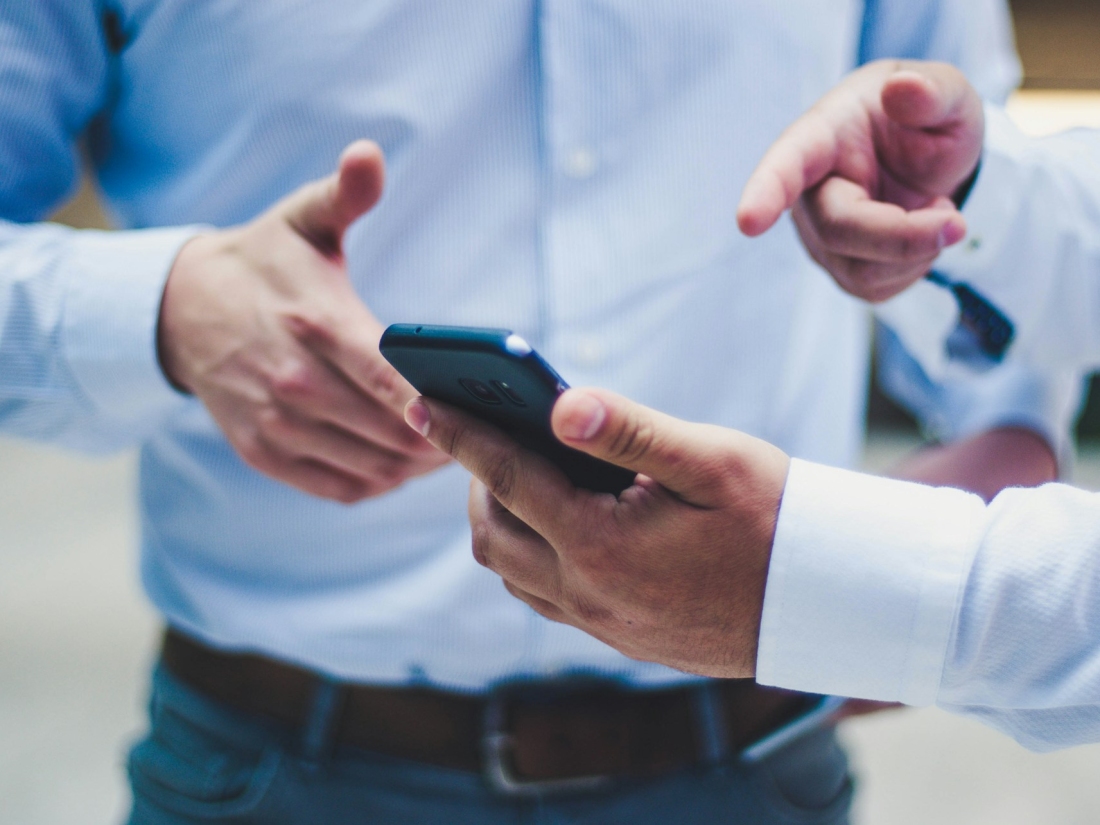 Zwei Männer, die ein Smartphone in der Hand halten. - Gesundheitsmanagement Studium