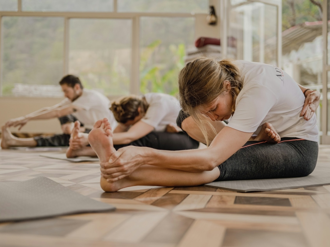 Gruppe sitzt auf dem Boden und macht Yoga – Sport studieren Ratgeber