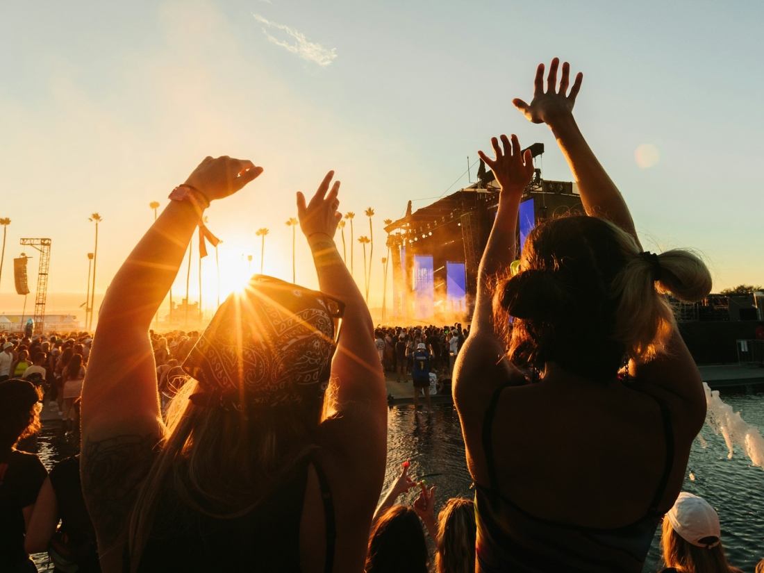 Personen feiern bei einem Open-Air-Festival im Sonnenuntergang – Symbolbild für Musik- und Kulturevents im Veranstaltungsmanagement Studium.