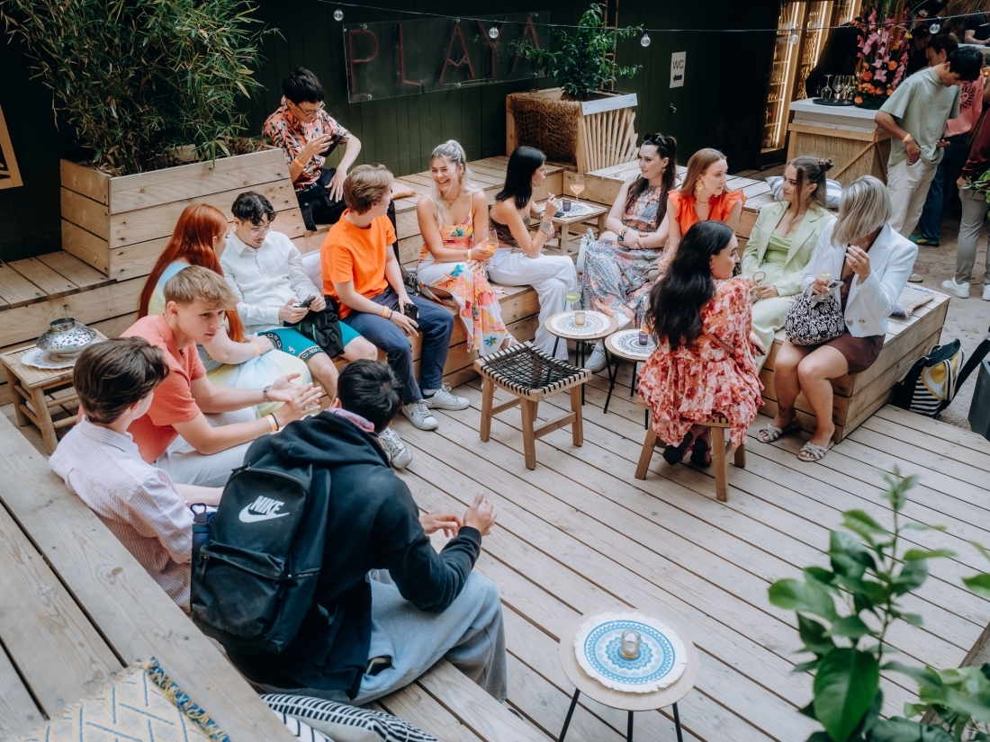 Studierende sitzen in entspannter Runde bei einer Campus-Veranstaltung – Symbol für Gemeinschaft und Netzwerken im Veranstaltungsmanagement Studium