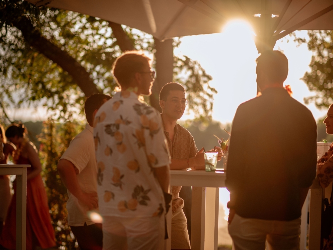 Studierende im Gespräch bei Sonnenuntergang während einer Outdoor-Veranstaltung – Symbol für Networking und Praxisnähe im Veranstaltungsmanagement Studium