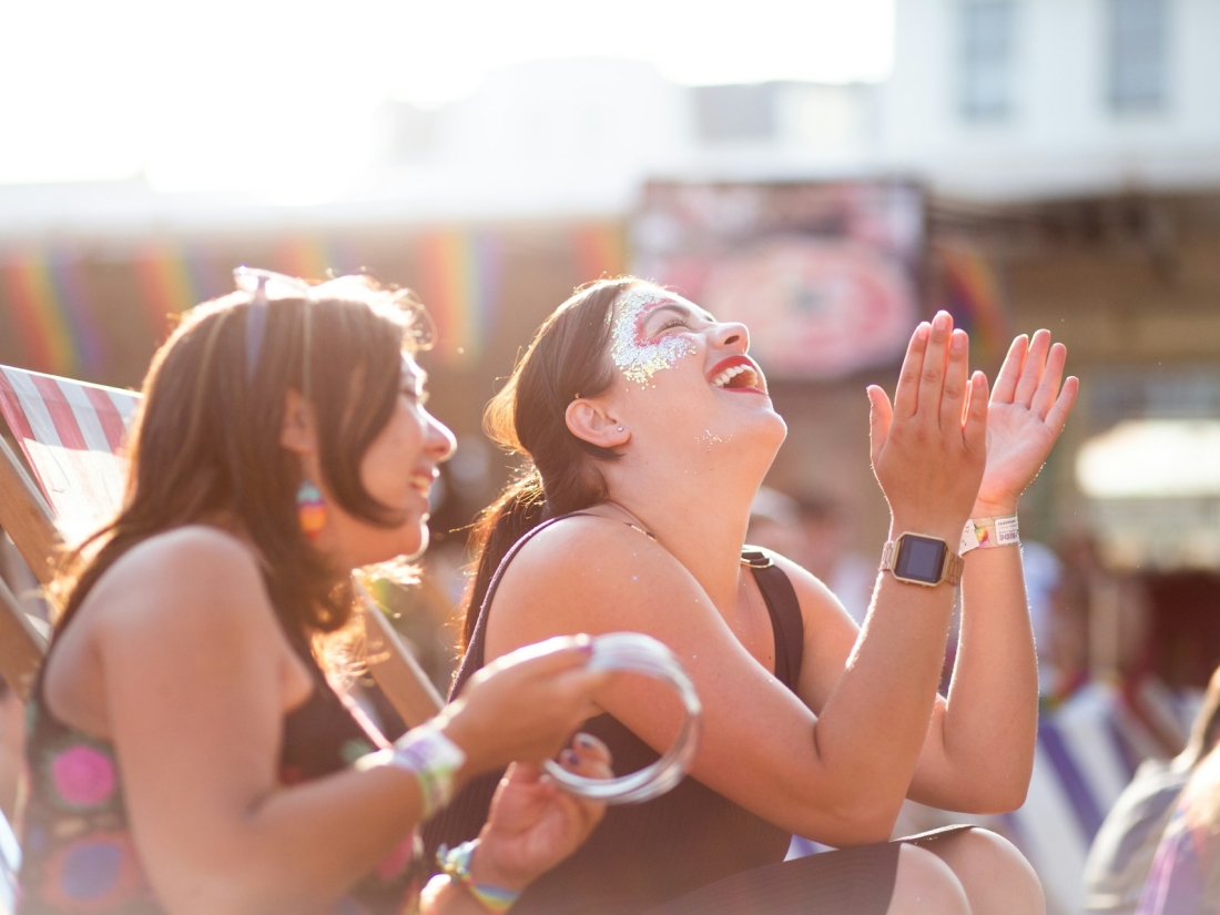 Zwei junge Personen genießen ein Sommerfestival und lachen in der Sonne – Symbol für Festival- und Entertainment-Bereich im Veranstaltungsmanagement Studium 8. Wie