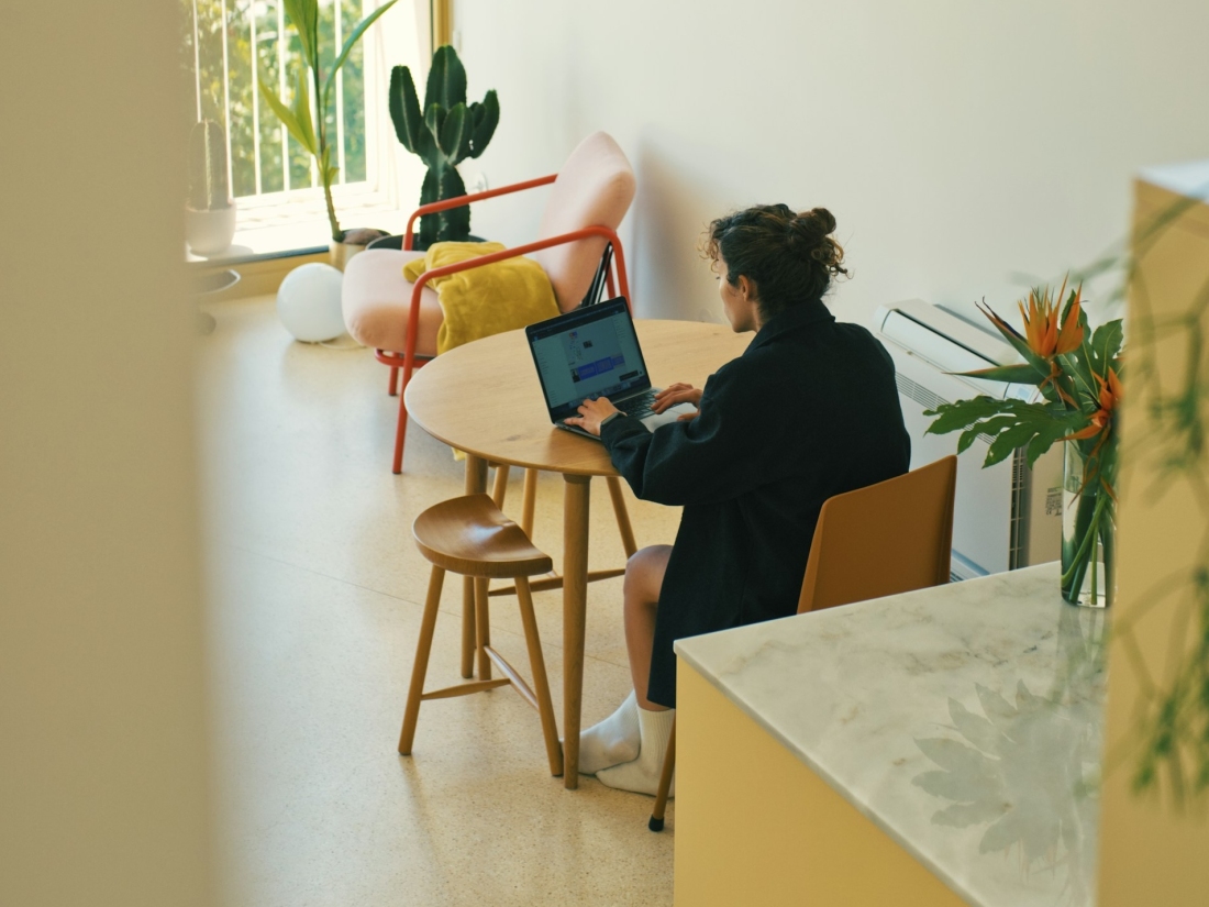 Alt-Text: Student arbeitet am Laptop in moderner Wohnung – Sinnbild für flexibles Lernen im Psychologie Studium.
