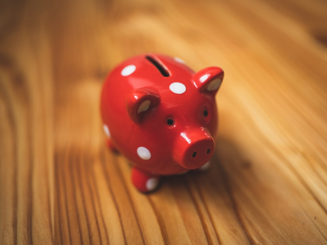 Rotes Sparschwein mit weißen Punkten auf einem Holztisch